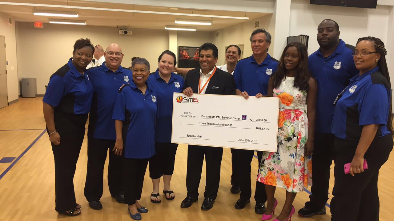 Dr. Johnny Garcia holding a $3,000 SimIS sponsorship check with PAL Summer Camp staff, dated June 25th, 2018.