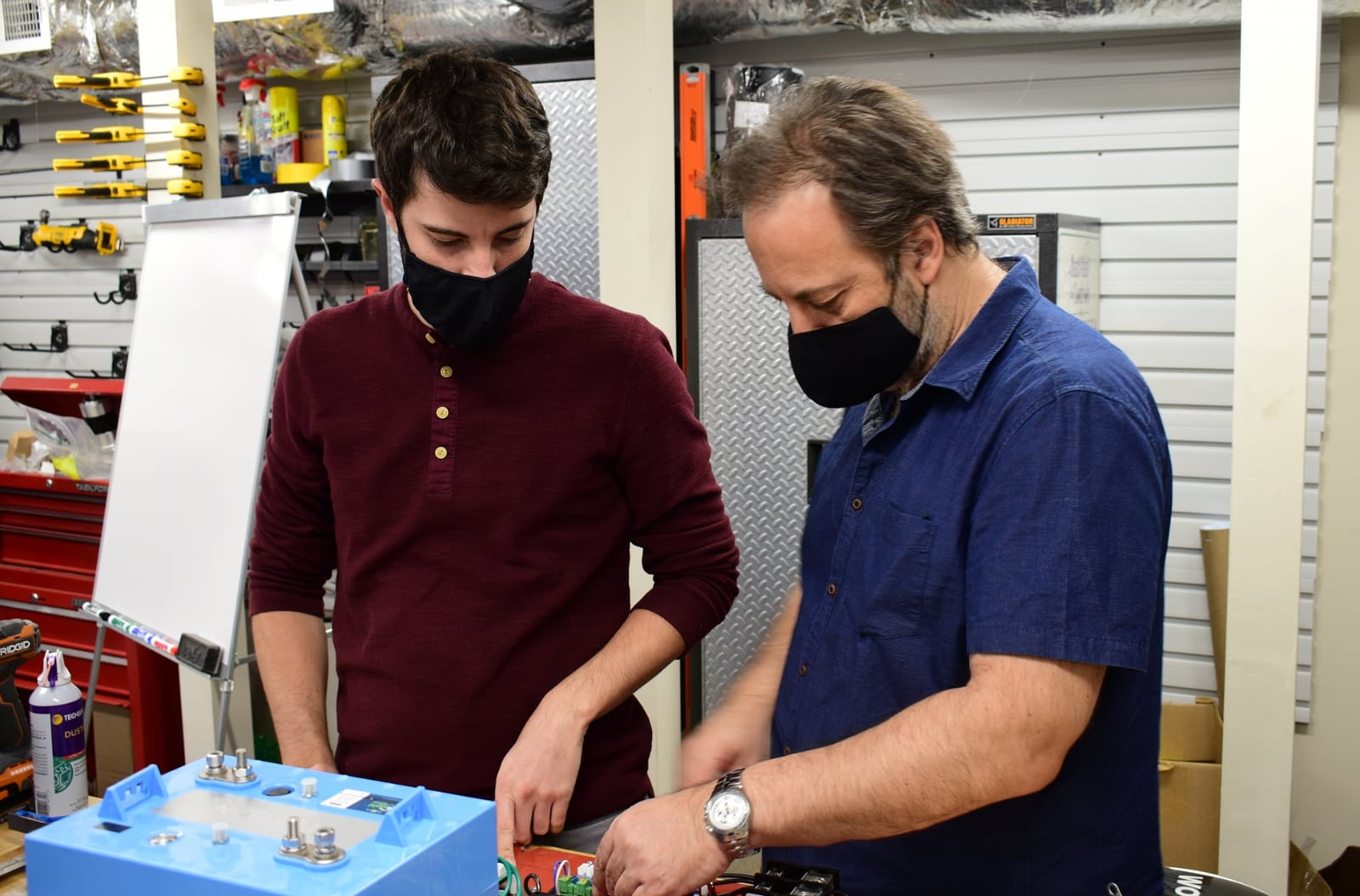 Two masked SimIS engineers working on HTT robot components in the Virginia Beach fabrication shop.