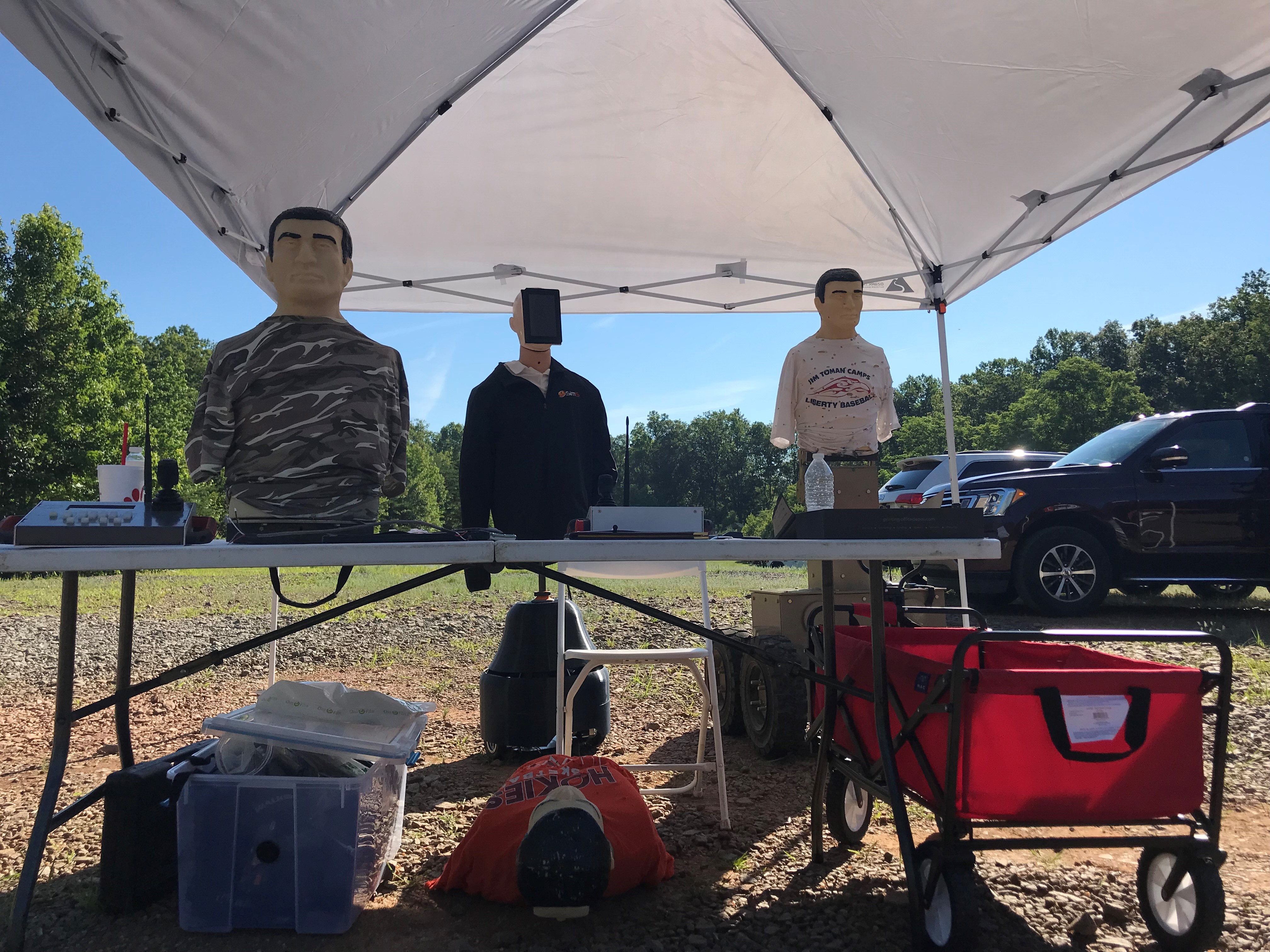 Three mannequin-style HTT targets displayed under a tent at the TSSi expo, one wearing a SimIS jacket.
